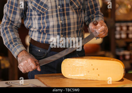 Geschäftsinhaber Schneiden von Käse in seinem Geschäft Stockfoto