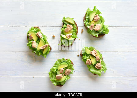 Gesunde Sandwichs mit Thunfisch, Avocado und Salatblätter. Lecker Thunfisch Sandwiches zum Frühstück oder Mittagessen über hellen Hintergrund. Gesunden Snack. Zu Stockfoto