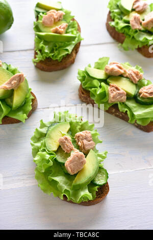 Sandwichs mit Thunfisch, Avocado und Salatblätter auf hellem Holz Tisch. Lecker Thunfisch Brötchen zum Frühstück oder Mittagessen. Gesunden Snack. Stockfoto