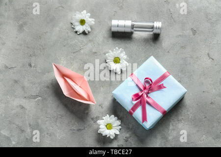 Geschenkbox mit Flasche Parfüm, origami Boot und Blumen auf grunge Hintergrund Stockfoto