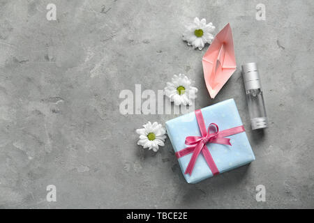 Geschenkbox mit Flasche Parfüm, origami Boot und Blumen auf grunge Hintergrund Stockfoto