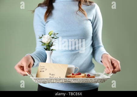 Frau mit Fach mit leckerem Frühstück und Grußkarte für Mutter, Nahaufnahme Stockfoto