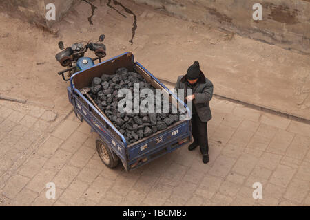 Chinesischen Mann, der durch eine 3-Rad Motorrad Durchführung Kohle in die alte Stadt von Pingyao. Draufsicht von oben gesehen. Pingyao, China - Dezember 26, 201 Stockfoto