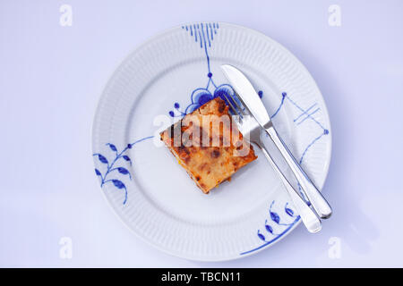 Stück Lasagne auf einem Teller mit Messer und Gabel. Top Bild anzeigen Stockfoto