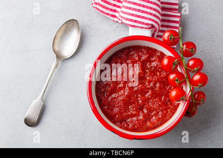 Traditionelle Tomatensauce in Kochtopf. Ansicht von oben. Kopieren Sie Platz. Grauer Hintergrund. Stockfoto