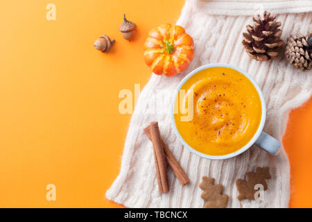 Kürbis Latte mit Gewürzen. Versoffenes Cocktail. Orange hinterlegt. Ansicht von oben. Kopieren Sie Platz. Stockfoto