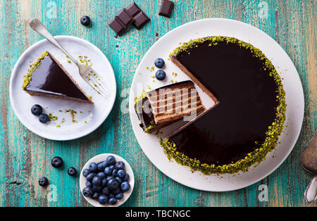 Schokoladenkuchen auf einem weißen Teller. Blau Holz- Hintergrund. Ansicht von oben. Stockfoto