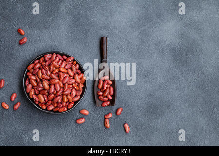 Rote Bohnen in einem schwarzen Schüssel auf grauem Stein Hintergrund. Ansicht von oben. Kopieren Sie Platz. Stockfoto