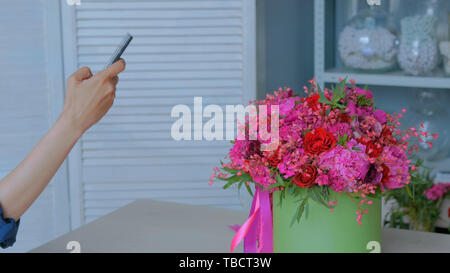 Frau unter Foto des Schönen Blumenstrauß mit Smartphone Stockfoto