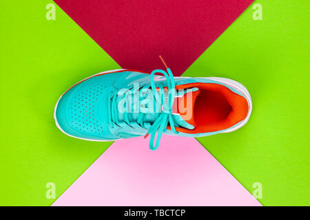 Rot, Hellblau, Weiß neu Tennisschuh im Studio Schuß über Grün, Pink, Lila, Hintergrund. Direkt von oben. Stockfoto