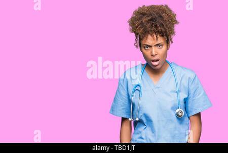 Junge afrikanische amerikanische Ärztin Frau über isolierte Hintergrund im Schock Gesicht, schaut skeptisch und sarkastisch, mit offenem Mund überrascht Stockfoto
