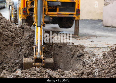 Bagger gräbt ein Graben. Reparaturarbeiten im Innenhof eines Wohnhauses. Stockfoto