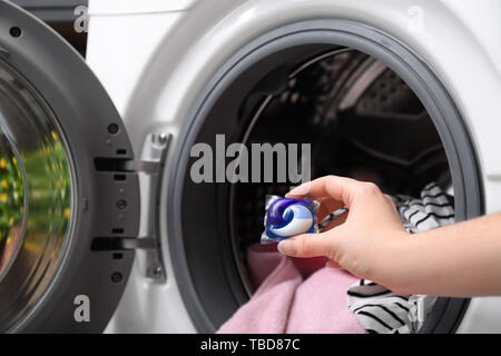 Frau putting pod Waschmittel in der Waschmaschine mit Wäscheservice, Nahaufnahme Stockfoto