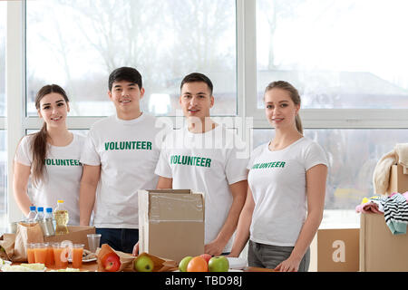 Die jungen Freiwilligen mit Lebensmitteln für arme Menschen in Innenräumen Stockfoto