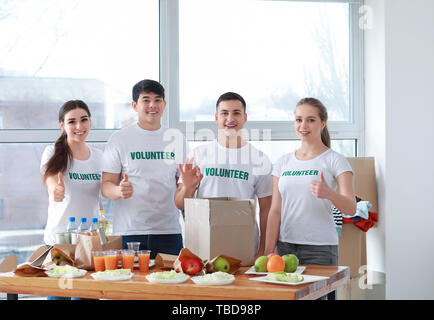 Die jungen Freiwilligen mit Lebensmitteln für arme Menschen in Innenräumen Stockfoto