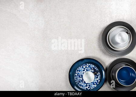 Leere blaue und schwarze Platten mit Tassen auf grauem Hintergrund, Ansicht von Oben, Kopieren Raum Stockfoto
