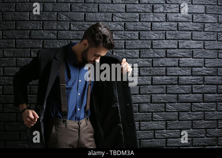 Modische junge Mann gegen dunkle Mauer Stockfoto