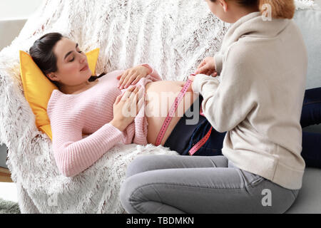 Doula messen Bauch der schwangeren Frau zu Hause Stockfoto