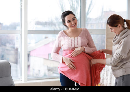 Doula mit schwangeren Frau zu Hause Stockfoto