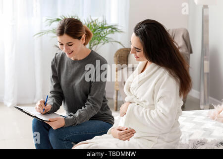 Doula mit schwangeren Frau zu Hause Stockfoto