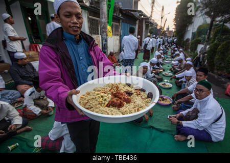 Mai 31, 2019, Jakarta, Jakarta, Indonesien - ein Mann mit kebuli Reis während Iftar sammeln in Kampung Arab, West Jakarta am 31. Mai 2019. Die Einwohner von Kampung Arab (Arabisches Dorf) in Pekojan, West Jakarta, halten die jährliche iftar Versammlung auf jeden 27. des Ramadan. Die Tradition begann im 18. Jahrhundert. Nicht nur Einheimische, die Teilnehmer kommen auch aus anderen Städten W. Java und C Java. Die mit Spannung erwartete Veranstaltung ist auf den Straßen rund um das Hosting Moschee gesehen. Während die Tradition, beliebte Mitte Osten Gerichte wie kebuli Reis sind vorbereitet. Einzigartig an der Tradition ist für Männer statt, während w Stockfoto