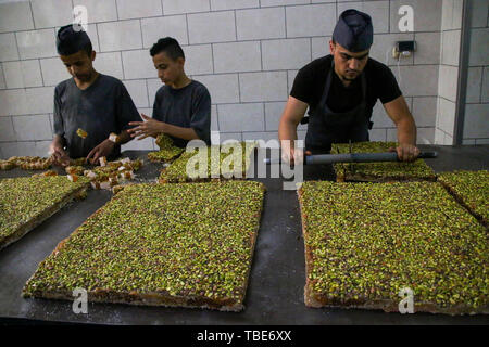 Mai 30, 2019 - Gaza, Gaza, Palästina. 30. Mai 2019. Fächer der traditionellen Süßigkeiten zu markieren das Ende des Ramadan sind in ein süßes Fabrik in Sabra Viertel von Gaza Stadt vorbereitet. Die Bonbons in die Fächer werden dann geschnitten, verpackt und zu den Verkäufern vor dem Eid al-Fitr feiern verteilt. Während die Bewohner des Gazastreifens machen Sie sich bereit für die kommende Eid al-Fitr, das Ende des muslimischen Fastenmonats Ramadan, die Verschlechterung der Wirtschafts- und Lebensbedingungen im Gazastreifen sind ihre Kaufkraft, die für das Fest. Einem Bericht der Palästinensischen Cent freigegeben Stockfoto