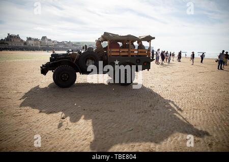 01. Juni 2019, France (Frankreich), Arromanches-Les-Bains: Eine historische jeep Laufwerke über den Goldenen Strand. Nach der Landung der alliierten Truppen im Zweiten Weltkrieg, einer der zwei künstliche Häfen (Mulberry B) gebaut wurde an der Küste von Arromanches-les-Bains, durch die Truppen und liefert an Land gebracht wurden. 06.06.2019 ist der 75. Jahrestag der Landung der alliierten Truppen in der Normandie (D-Day). Foto: Kay Nietfeld/dpa Stockfoto