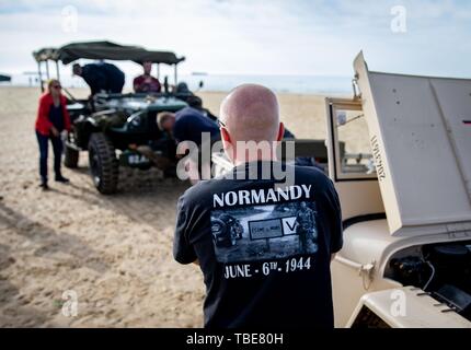 01. Juni 2019, France (Frankreich), Arromanches-Les-Bains: Eine Österreichische trägt ein T-Shirt mit der Aufschrift "Normandie - Juni-6 th-1944' vor seiner historischen Jeep. 06.06.2019 ist der 75. Jahrestag der Landung der alliierten Truppen in der Normandie (D-Day). Foto: Kay Nietfeld/dpa Stockfoto