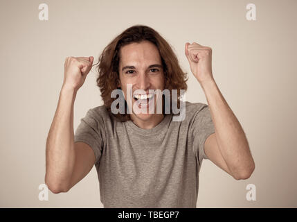 Portrait von sehr jungen Mann feiern in der Lotterie gewinnen oder mit großem Erfolg. Teenager mit langen Haaren und überrascht und glücklich Gesten. Stockfoto