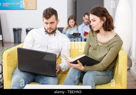 Paar junge Reisende mit Laptop Planung touristische Rundfahrt beim Stillstehen in Hostel Lobby Stockfoto