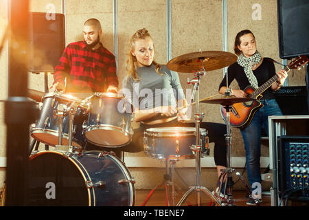 Emotionale happy positive weibliche Drummer mit ihren Bandkollegen üben im Proberaum leidenschaftlich Stockfoto