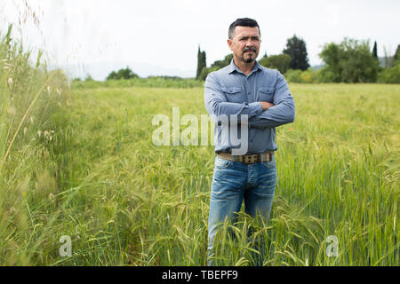 Portrait von schweren Reifen männlichen Landwirt in grün Weizenfeld Stockfoto