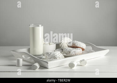 Fach mit leckeren Spezialitäten und ein Glas Milch auf weißen Tisch Stockfoto