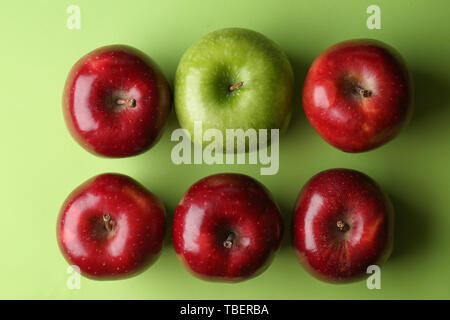 Green Apple unter roten Farbe Hintergrund. Konzept der Einzigartigkeit Stockfoto
