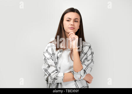 Portrait von schöne nachdenkliche Frau in Freizeitkleidung auf hellen Hintergrund Stockfoto