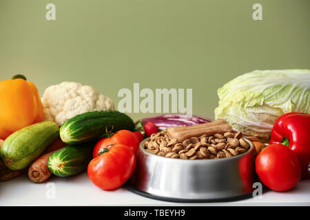 Schüssel mit trockenem Futter und frisches Gemüse auf dem Tisch Stockfoto
