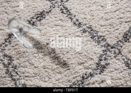 Glas Wasser auf Teppich verschüttet Stockfoto