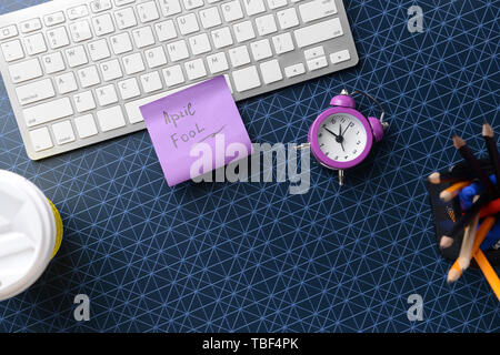 Computer Tastatur mit Briefpapier und Haftnotiz mit Text APRILSCHERZ auf farbigen Hintergrund Stockfoto