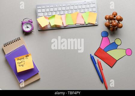 Computer Tastatur mit Schreibwaren und Haftnotizen auf grauem Hintergrund. April Fool's Day prank Stockfoto