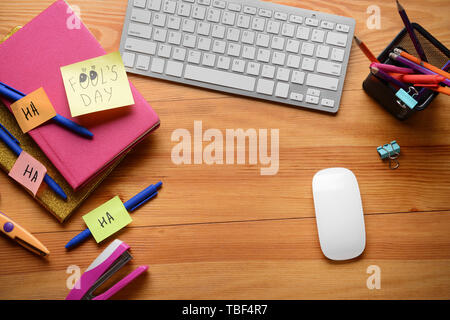 Computer Tastatur mit Briefpapier und Haftnotizen auf Holz- Hintergrund. April Fool's Day prank Stockfoto