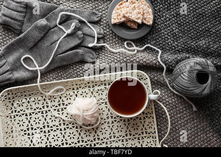 Fach mit Tasse heißen Tee, Threads und Knäckebrot auf Plaid Stockfoto