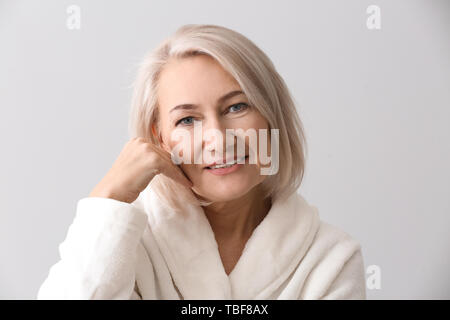 Reife Frau geben sich Massage auf hellen Hintergrund Gesicht Stockfoto