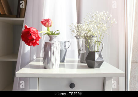 Schöne Blumen auf dem Tisch in der Nähe der Fenster Stockfoto