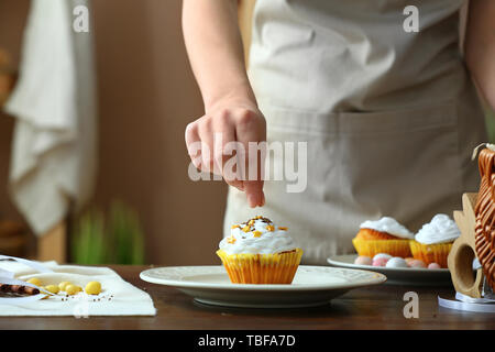 Frau dekorieren lecker Ostern Cupcake in der Küche Stockfoto