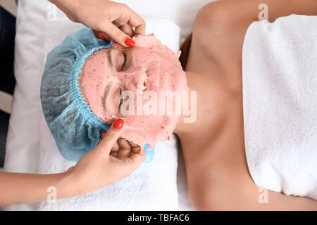 Kosmetiker aus Alginat Maske vom Gesicht der jungen Frau im Beauty Salon Stockfoto