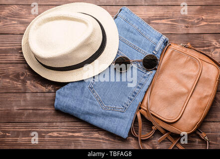 Hosen mit Tasche, Hut und Sonnenbrille auf hölzernen Hintergrund Stockfoto