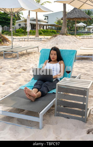 Jungen asiatischen Freiberufler auf Laptop am Strand arbeiten Stockfoto