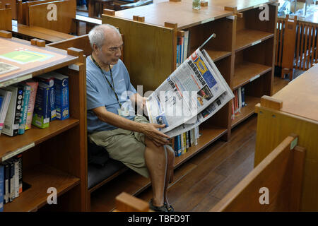 Ältere Menschen das Lesen einer Tageszeitung in Taipei Öffentliche Bibliothek Beitou Niederlassung in Beitou-Bezirk, Taipei, Taiwan Stockfoto