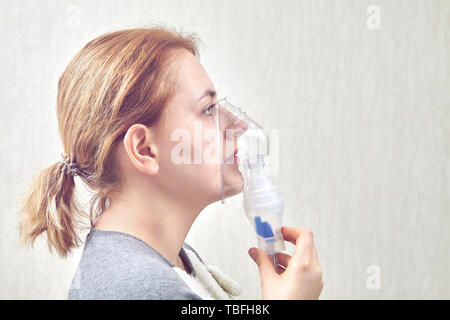 Mädchen verwendet Inhalator Inhalationsgerät für die Behandlung von Atemwegserkrankungen. Sie atmet mit Hilfe der Vernebler Kammer. Stockfoto