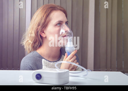 Junge Frau wird die Atmung mit Kompressor Vernebler System, das in der Behandlung von Erkrankungen der Atemwege verwendet. Stockfoto